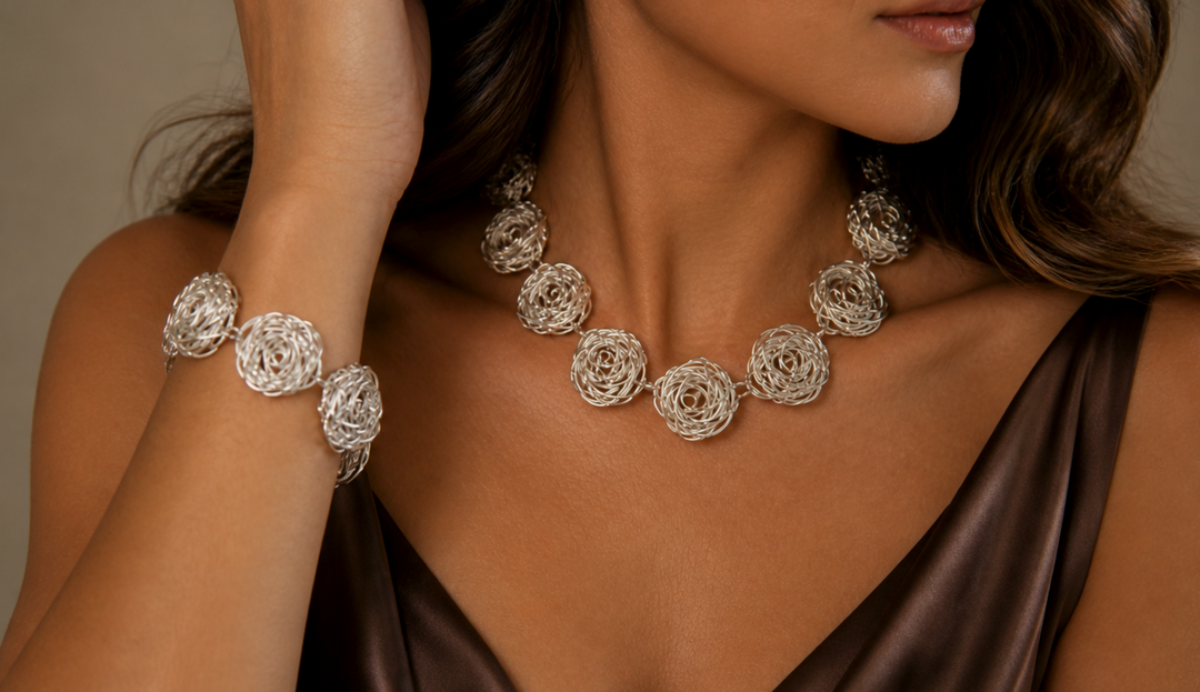Woman wearing a square-link sterling silver necklace and matching earrings by Renata Rubio 92.5, smiling in natural light