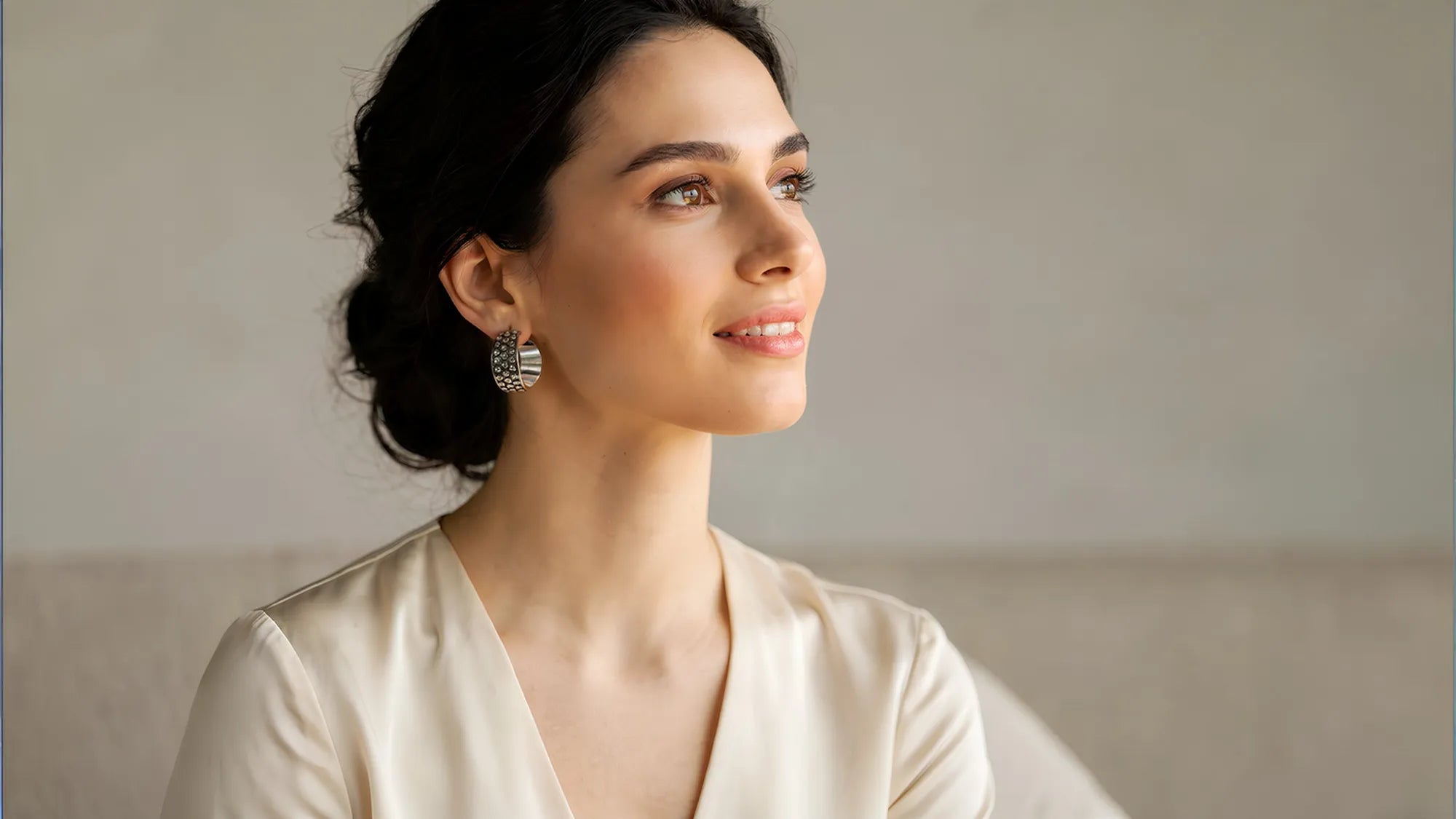 Woman with sterling silver earrings by Renata Rubio, wearing a beige top with a neutral background