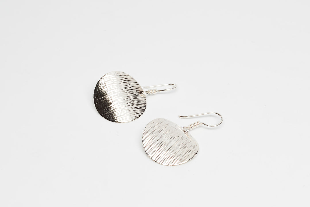 Edged silver disk earrings by Renata Rubio 92.5 – handcrafted, textured, and polished artisan jewelry.