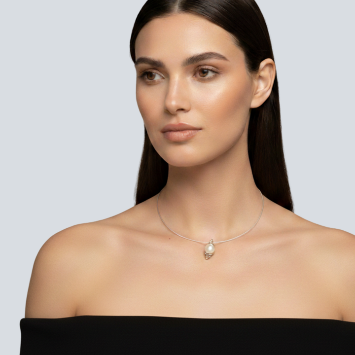 Woman wearing a Renata Rubio handcrafted sterling silver pearl pendant, double wrap silver design with vertical coiling form. Genuine round cultured pearl.